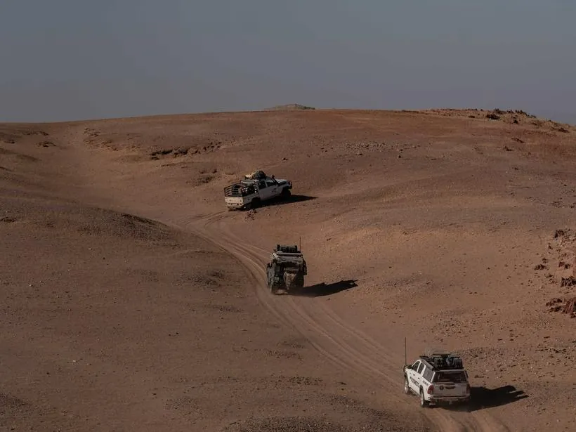 Vehicles working across dunes, seen from above
