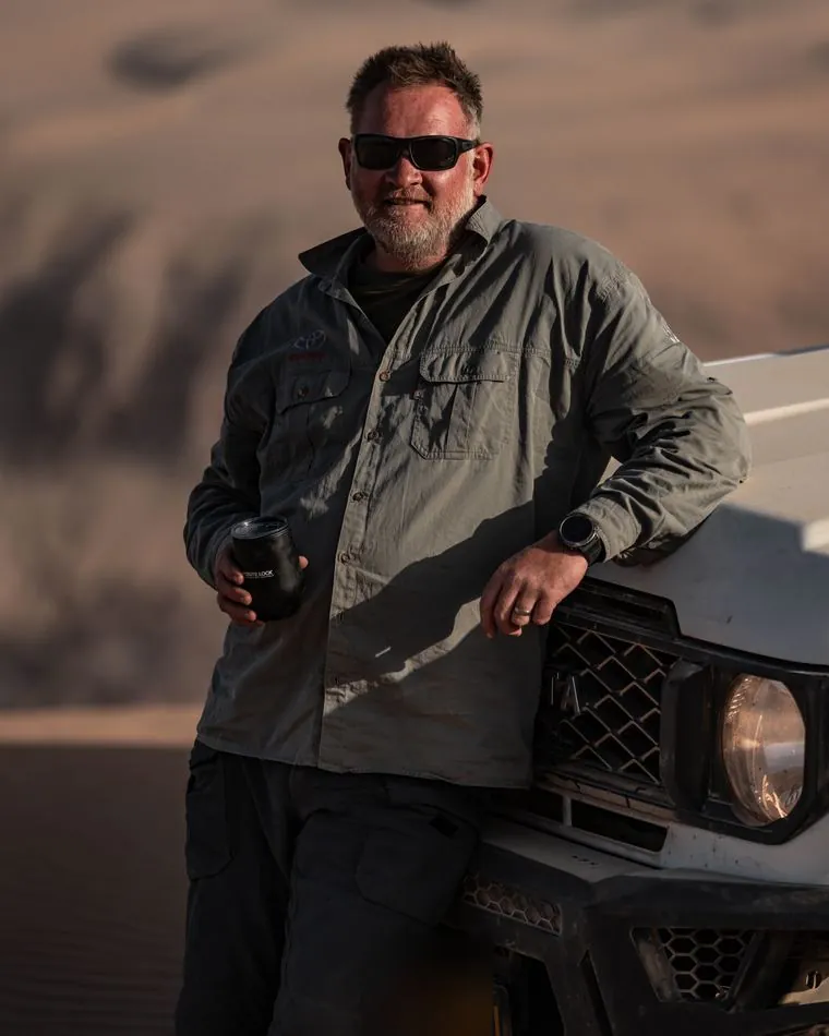 One of the guides beside a Land Cruiser 79 at golden hour