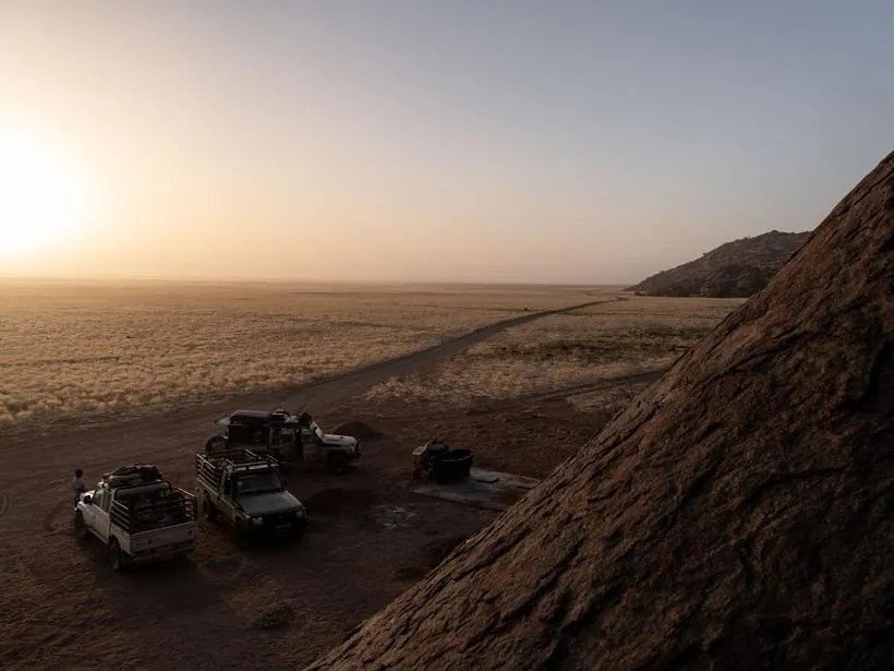 Camp at sunrise below a rock outcrop