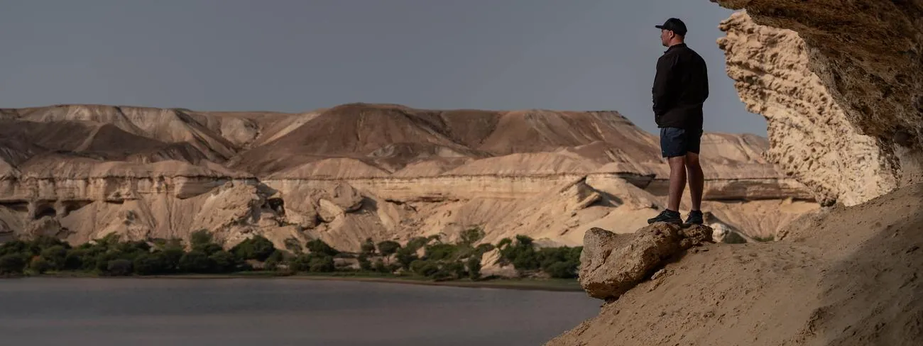 One of the crew standing above a river from a rock overhang