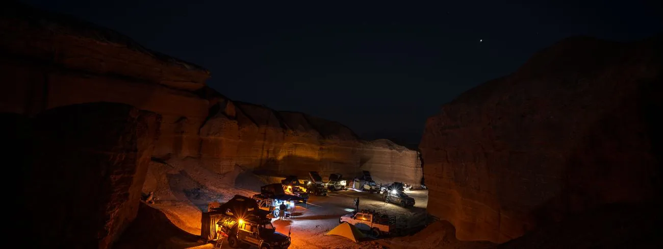The convoy camped at night inside a sandstone gorge, lit orange