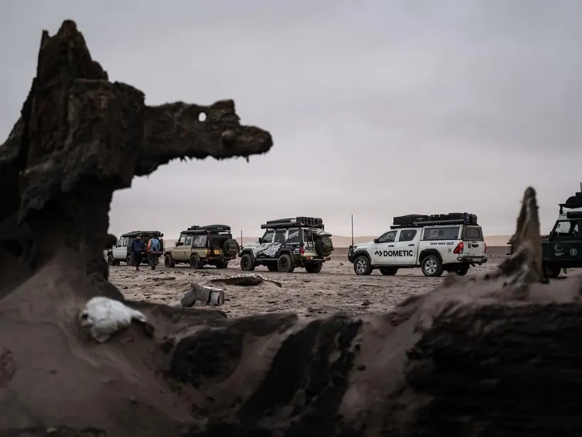 The convoy parked beyond the timbers of a wreck on the Skeleton Coast