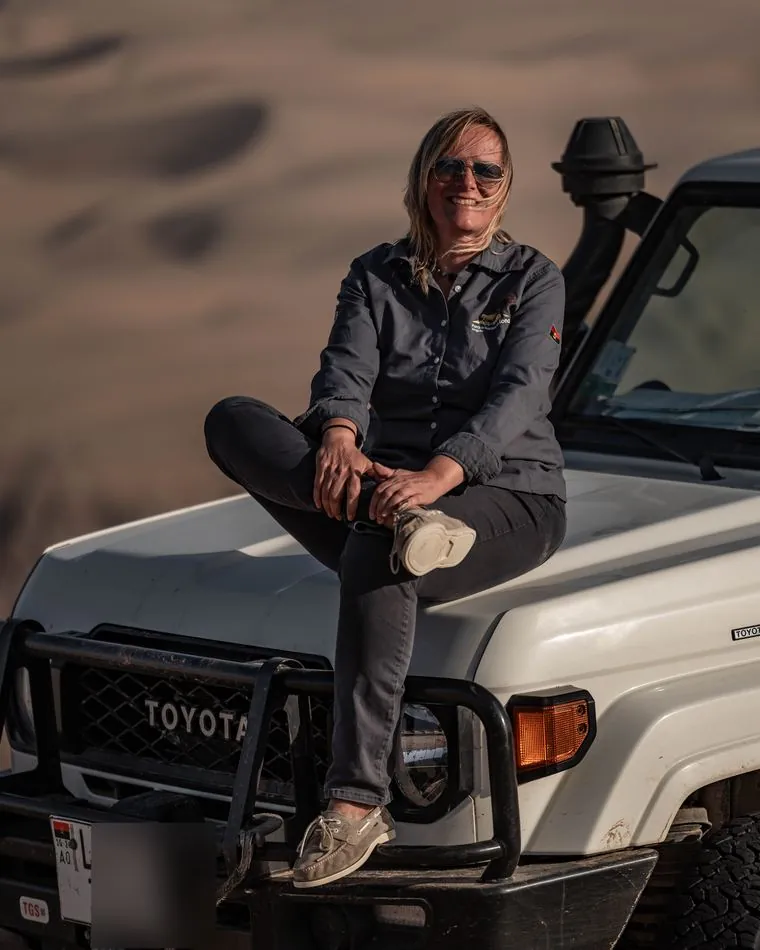 One of the guides on the bonnet of a Land Cruiser 79 in the dunes