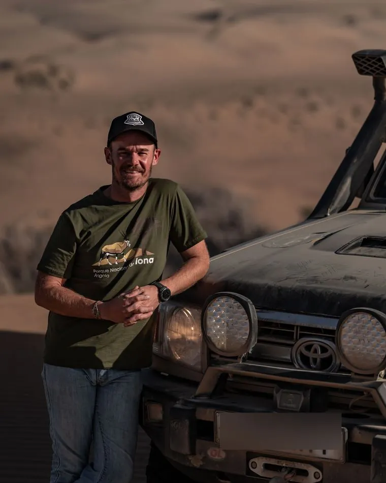 Willem van Eeden leaning against a Land Cruiser in the dunes