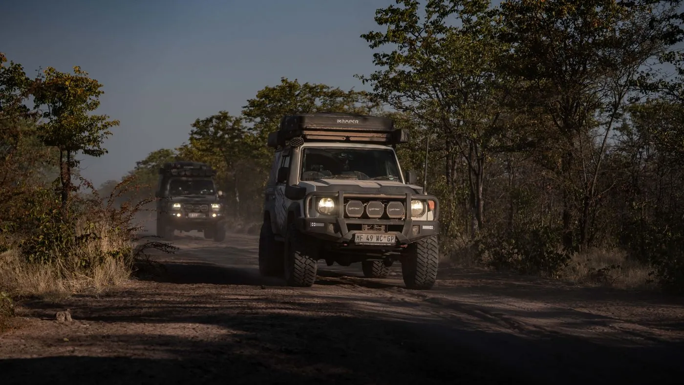 The convoy driving through dust with headlights on